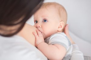 mother breast feeding and hugging baby